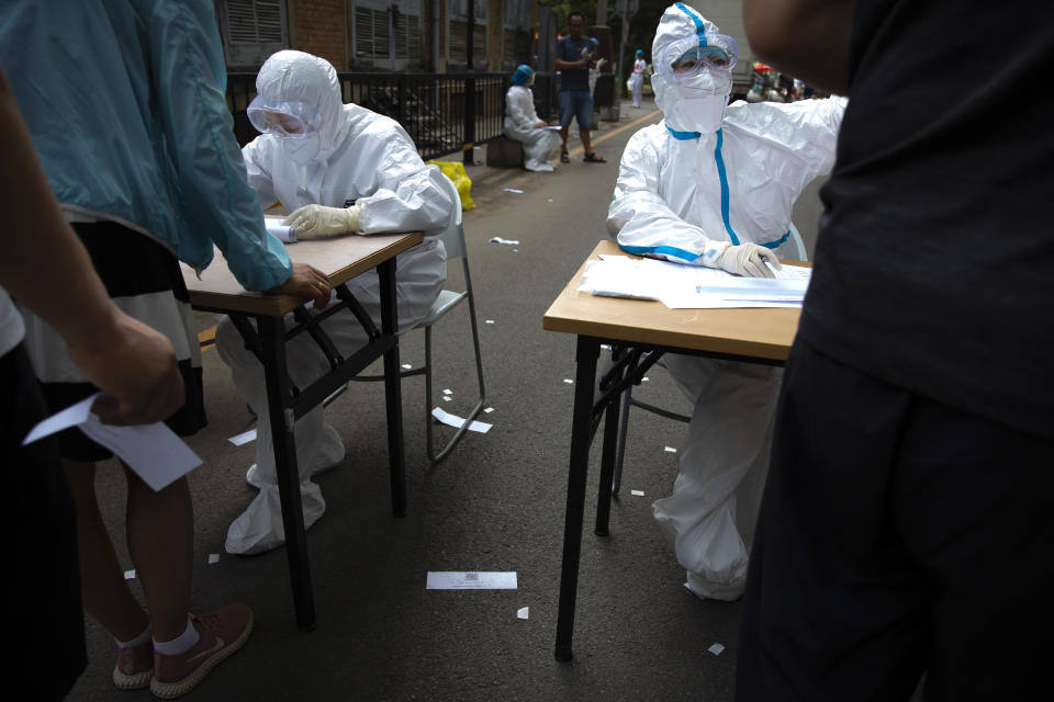 Workers in protective suits register people at a COVID-19 testing site for those who were potentially exposed to the coronavirus outbreak at a wholesale food market in Beijing, Wednesday, June 17, 2020. As the number of cases of COVID-19 in Beijing climbed in recent days following an outbreak linked to a wholesale food market, officials announced they had identified hundreds of thousands of people who needed to be tested for the coronavirus. (AP Photo/Mark Schiefelbein)