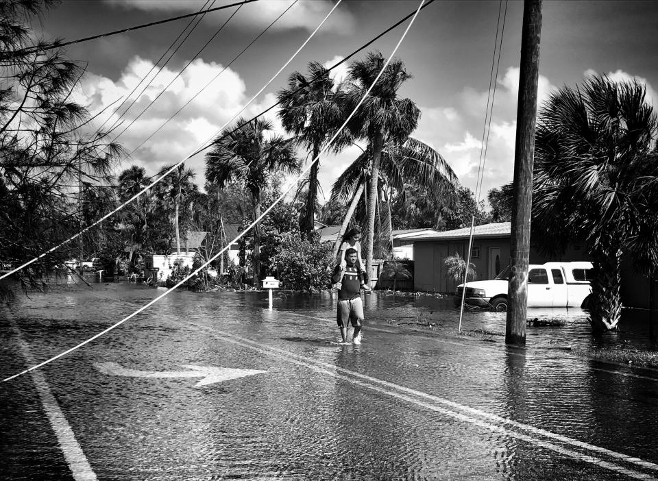 <p>A man carries a young girl on his shoulders in a flooded neighborhood in Bonita Springs, Fla. (Photo: Holly Bailey/Yahoo News) </p>