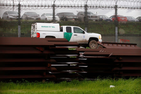 A U.S. border patrol vehicle drives past metal sections to be used to fix the border fence between Mexico and the U.S., as seen from Tijuana, Mexico, February 14, 2019. REUTERS/Jorge Duenes