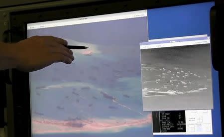 A U.S. Navy crewman aboard a P-8A Poseidon surveillance aircraft points to a computer screen purportedly showing Chinese construction on the reclaimed land of Fiery Cross Reef in the disputed Spratly Islands in the South China Sea in this still image from video provided by the United States Navy May 21, 2015. REUTERS/U.S. Navy/Handout via Reuters
