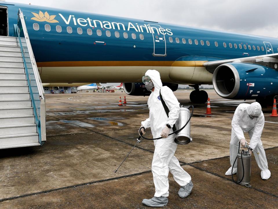  Workers wearing protective suits prepare to disinfect a Vietnam Airlines plane amid concerns of the spread of the COVID 19 coronavirus at Noi Bai International Airport in Hanoi on March 3, 2020. (Photo by Nhac NGUYEN : AFP