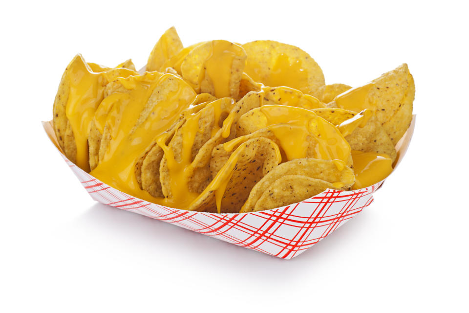 A basket of tortilla chips covered in melted cheese