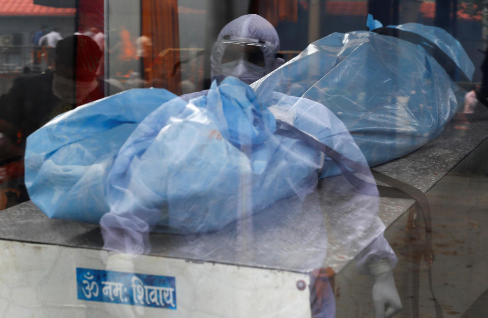 A health worker wearing personal protective equipment (PPE) suit stands as a body of a man, who died due to the coronavirus disease (COVID-19), is seen inside an ambulance at a crematorium in New Delhi, India September 7, 2020. / Credit: ADNAN ABIDI/REUTERS