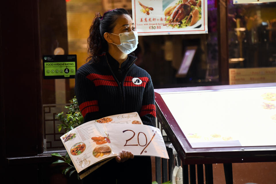 FILE - In this Sept. 22, 2020 file photo, a waitress wears a protective mask as she stands at the door of a restaurant in Soho, in London, Tuesday, Sept. 22, 2020. Figures released Friday, Oct. 9, 2020 from the Office for National Statistics show that the British economy grew by far less than anticipated during August, raising concerns that the recovery from the coronavirus recession was already stuttering even before the reimposition of an array of lockdown restrictions. (AP Photo/Alberto Pezzali, file)