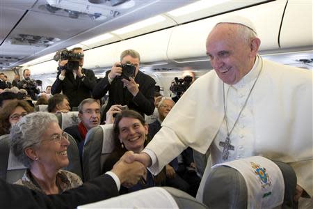 Pope Francis (R) greets journalists aboard the papal flight on his way to Amman, May 24, 2014. REUTERS/Andrew Medichini/Pool