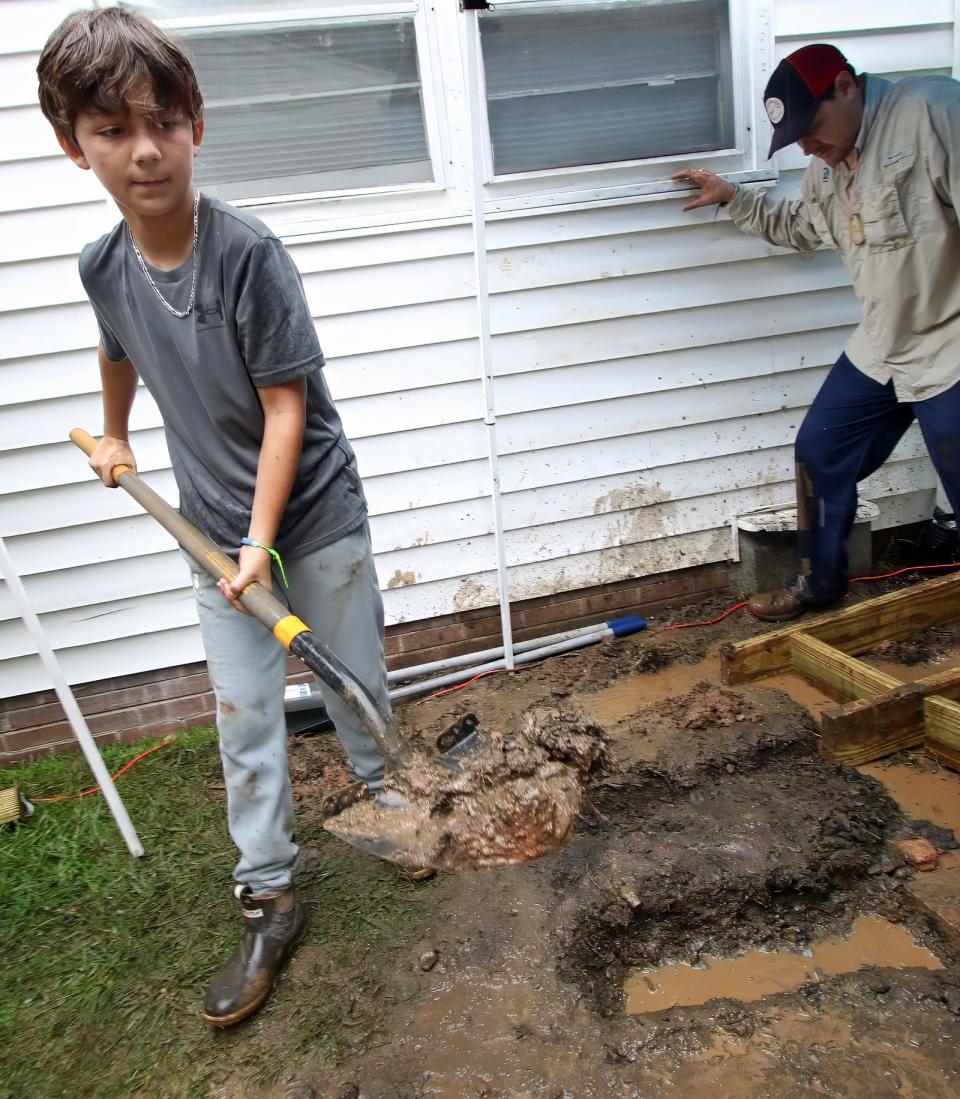 Twelve-year-old Lance Lucas shovels mud as he and others with Carolina Cross Connections  construct a ramp at a home on South Marietta Street in the rain Thursday morning, June 22, 2023.