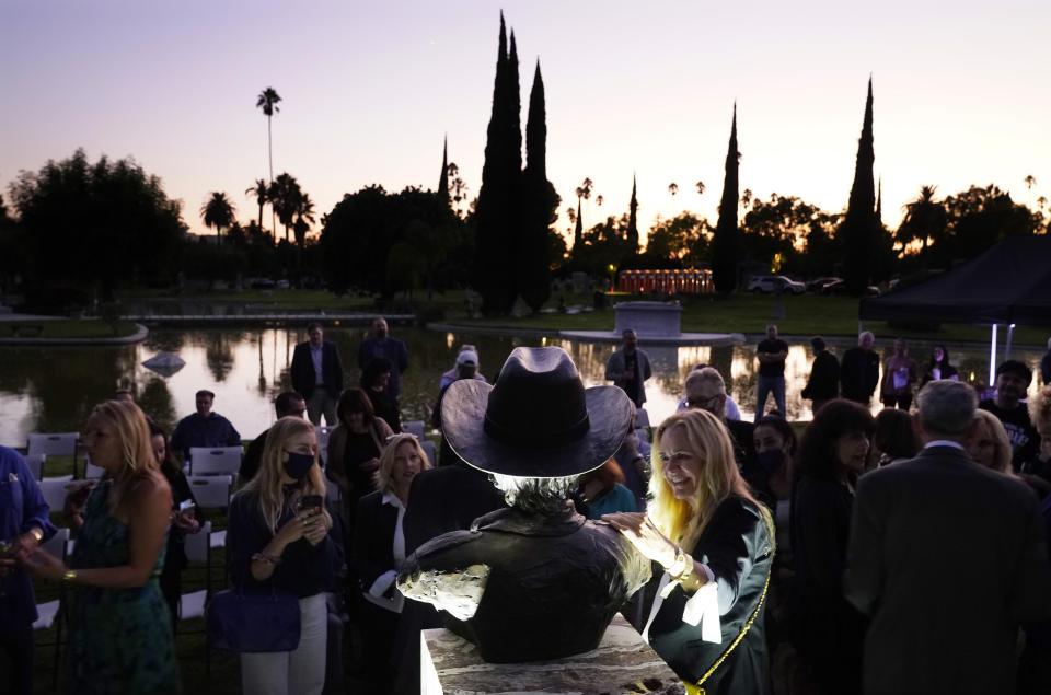 Guests gather around a newly unveiled memorial sculpture of the late actor Burt Reynolds following a ceremony at Hollywood Forever Cemetery, Monday, Sept. 20, 2021, in Los Angeles. Reynolds died in 2018 at the age of 82. (AP Photo/Chris Pizzello)