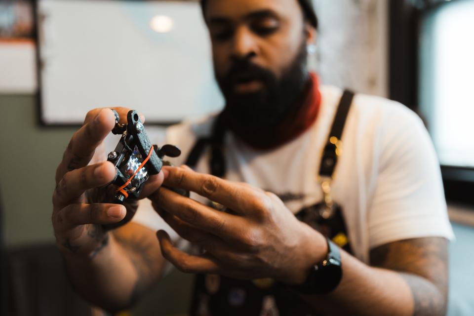 Adrien Clark sets the depth of a tattoo needle.