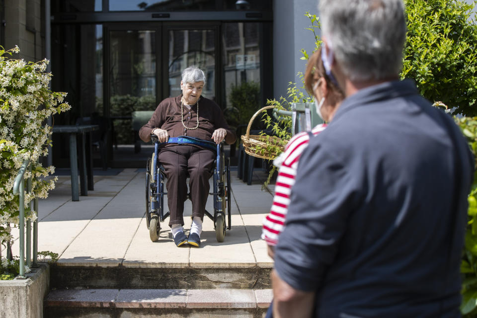 Carmela Bergamelli, 87, sits in a wheelchair at a safe distance as she talks to her family at the Martino Zanchi Foundation nursing home in Alzano Lombardo, Italy, Friday, May 29, 2020. (AP Photo/Luca Bruno)