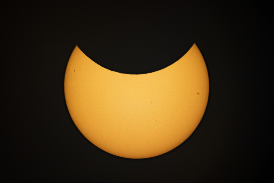 The moon appears to take a bite out of the sun and blocks the sun's upper half.