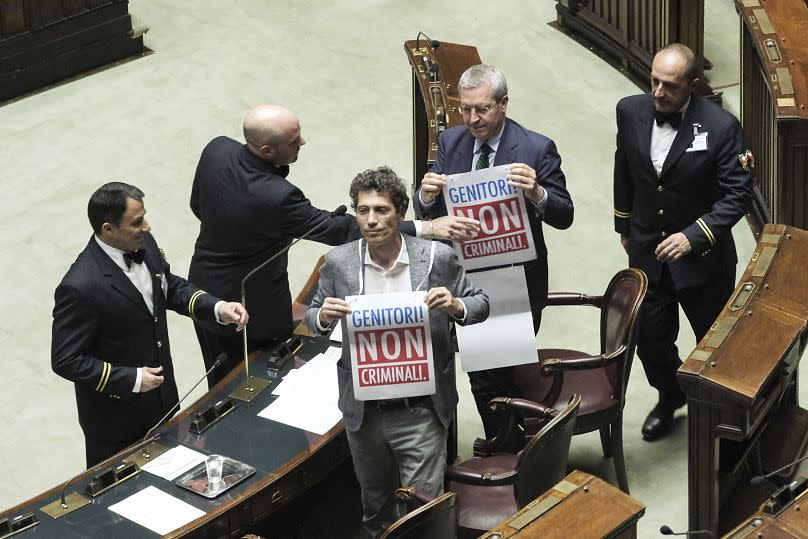 +Europa&apos;s lawmakers Riccardo Magi, and Benedetto Della Vedova hold placards reading in Italian: &quot;Parents not criminals&quot; in Lower Chamber during surrogacy debate