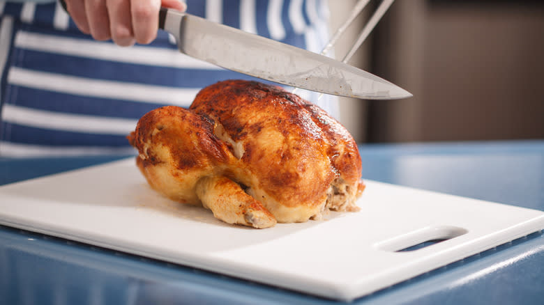 rotisserie chicken with a knife in chef's hand