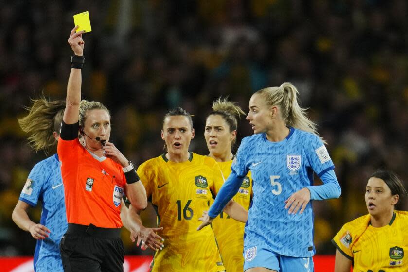 Referee Tori Penso shows a yellow card to England's Alex Greenwood, second from right, during.