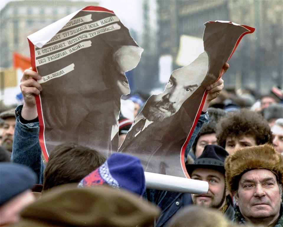 FILE - A participant in a pro-democracy rally shows his disgust for the Soviet system by ripping apart a portrait of its founder, Vladimir Lenin, in Moscow, Russia, on Sunday, Feb. 25, 1990. A century after Lenin’s 1924 death, the once-omnipresent image of Lenin is largely an afterthought in modern Russia, despite the famous lines by poet Vladimir Mayakovsky: "Lenin lived, Lenin lives, Lenin will live." (AP Photo/Alexander Zemlianichenko, File)