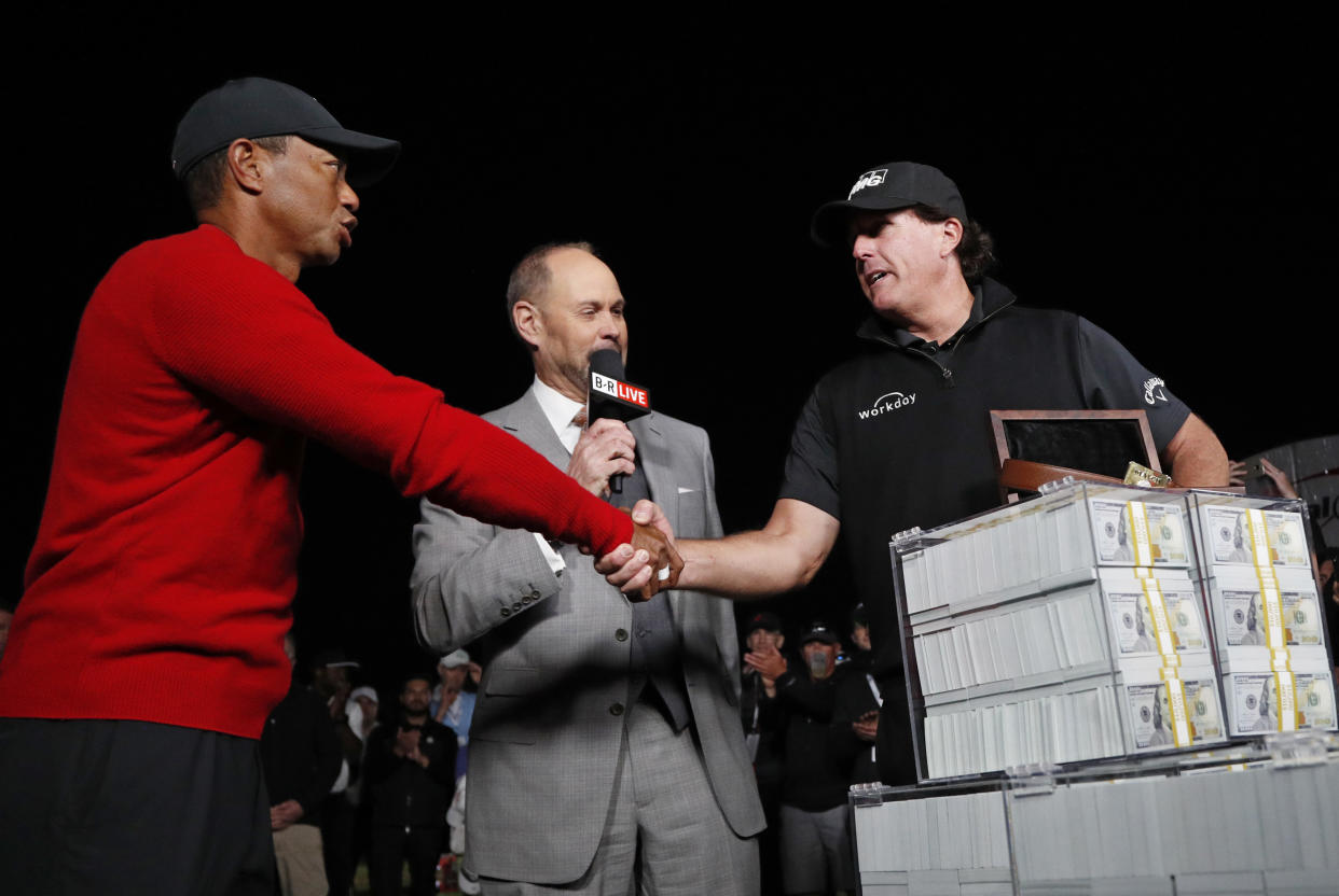 Tiger Woods, left, shakes hands after losing a golf match to Phil Mickelson, right, at Shadow Creek golf course, Friday, Nov. 23, 2018, in Las Vegas. (AP Photo/John Locher)