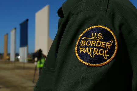 A border patrol officer stands next to some of U.S. President Donald Trump's eight border wall prototypes as they near completion along U.S.- Mexico border in San Diego, California, U.S., October 23, 2017. REUTERS/Mike Blake