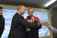 Russia's President Vladimir Putin (L) greets a participant while standing next to President of the Canadian Olympic Committee Marcel Aubut as he visits Team Canada House at the Olympic Park during the Sochi 2014 Winter Olympics Games, February 14, 2014. REUTERS/Mikhail Klimentyev/RIA Novosti/Kremlin (RUSSIA - Tags: POLITICS OLYMPICS SPORT) ATTENTION EDITORS - THIS IMAGE HAS BEEN SUPPLIED BY A THIRD PARTY. IT IS DISTRIBUTED, EXACTLY AS RECEIVED BY REUTERS, AS A SERVICE TO CLIENTS