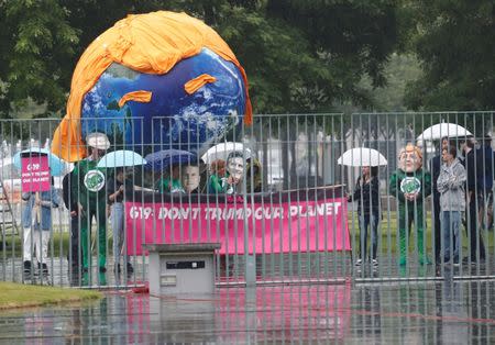 Activists hold a banner, behind a giant globe, as they protest under the rain in Berlin, Germany June 29, 2017. REUTERS/Frabrizio Bensch