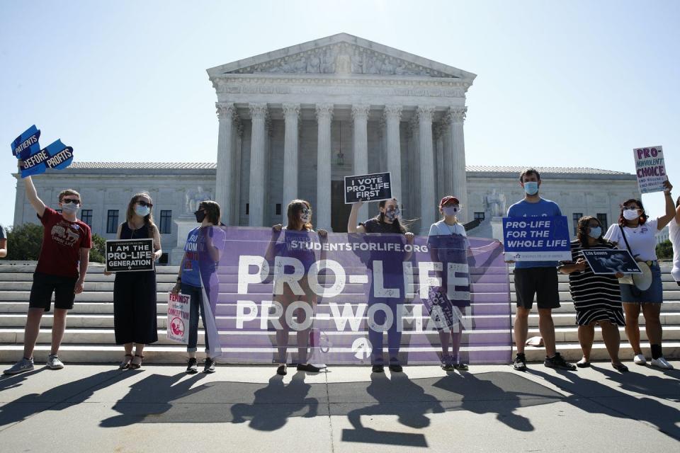 A group of people holding signs in front of the Supreme Court building