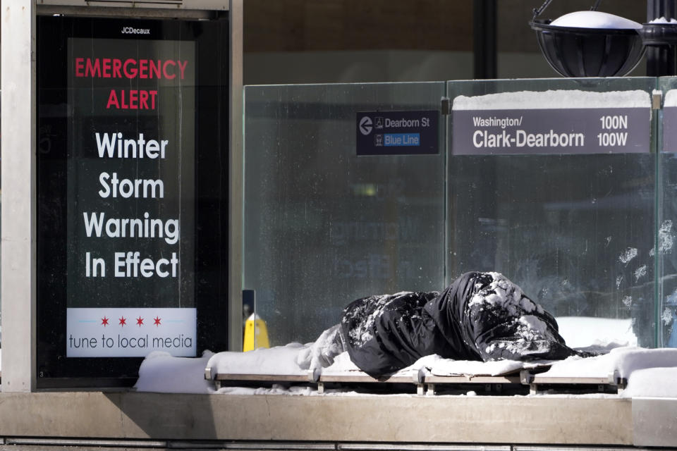 A homeless man Tuesday, Feb. 16, 2021, sleeps at the Chicago Transit Authority's Clark & Dearborn bus station, the morning after a snowstorm dumped up to 18 inches in the greater Chicago area. (AP Photo/Charles Rex Arbogast)