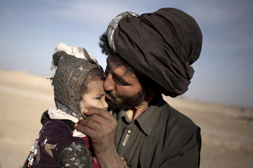 FILE - A nomad kisses his young daughter while watching his herd in Marjah, Helmand province, Afghanistan on Oct. 20, 2012. (AP Photo/Anja Niedringhaus, File)