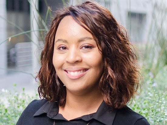 A woman wearing a black shirt smiles to the camera