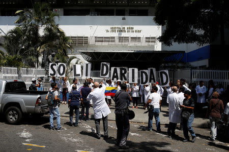 Venezuelans, including doctors, hold banners that read "Solidarity" as they gather outside a public children hospital during an ongoing blackout in Caracas, Venezuela March 10, 2019. REUTERS/Marco Bello