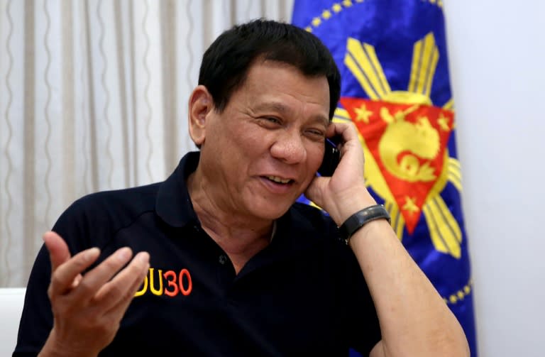 Philippines' President Rodrigo Duterte talks to US President-elect Donald Trump on the phone at Legaspi Suites in Davao City