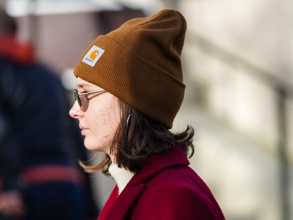 Woman wearing tan Carhartt beanie with red coat