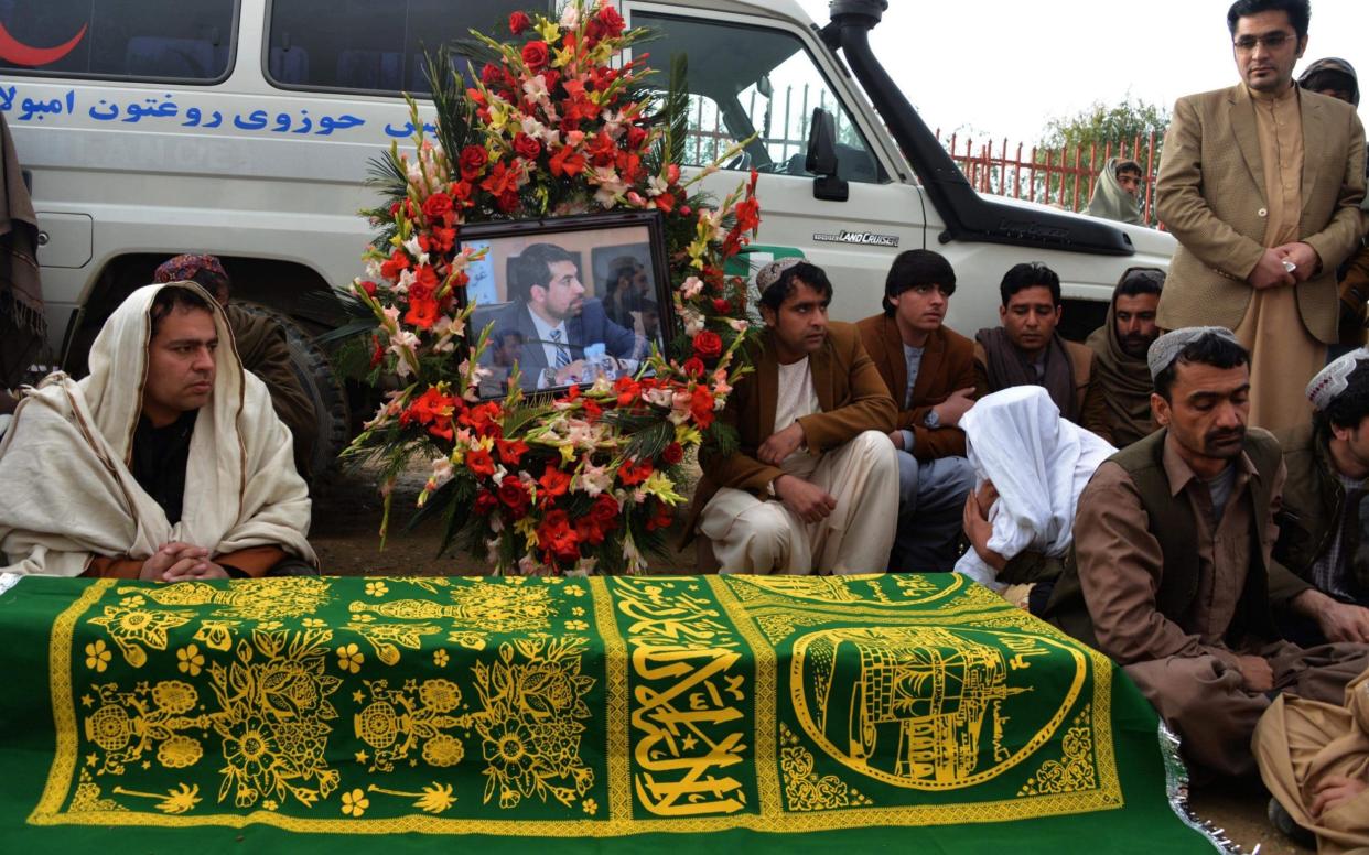 Afghan mourners sit around the coffin of Mufti Ahmad Farzan, a member of the High Peace Council, who died during an attack by armed insurgents at Kabul's Intercontinental hotel - AFP