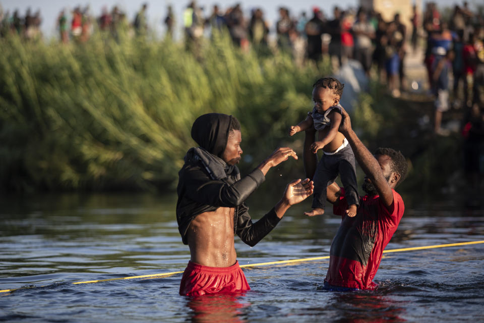 Men lift a baby over the waters of the Rio Grande river as migrants, many from Haiti, wade across the from Del Rio, Texas, to return to Ciudad Acuña, Mexico, Monday, Sept. 20, 2021, to avoid deportation from the U.S. The U.S. is flying Haitians camped in a Texas border town back to their homeland and blocking others from crossing the border from Mexico in a massive show of force. (AP Photo/Felix Marquez)