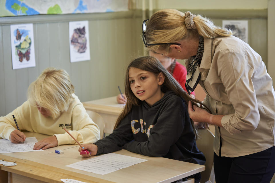 A teacher helps a student practice her handwriting at the Djurgardsskolan elementary school in Stockholm, Sweden, Thursday, Aug. 31, 2023. As children across Sweden have recently flocked back to school after the summer vacation, many of their teachers are putting a new emphasis on printed books, quiet reading hours, and practicing handwriting as the country's yearslong focus on the digitalization of classrooms has come under scrutiny. (AP Photo/David Keyton)