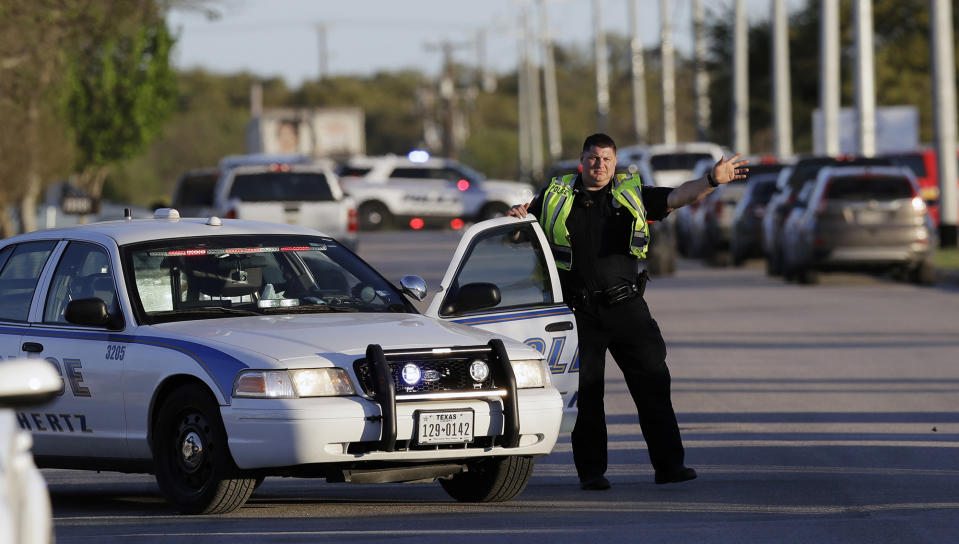 <p>A police officer stops a vehicle at a check point in front of a FedEx distribution center where a package exploded, Tuesday, March 20, 2018, in Schertz, Texas. (Photo: Eric Gay/AP) </p>