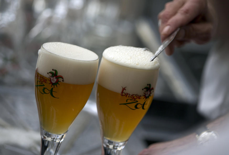 FILE - In this file photo dated Thursday, May 26, 2016, a workers scrapes the foam off of a glass of beer before serving, in Bruges, Belgium. Bars and restaurants in Belgium will be allowed to reopen starting Monday June 8, 2020, under strict coronavirus conditions, with tables spaced at least 1.5 meters apart, with patrons being asked to support their locals. (AP Photo/Virginia Mayo, FILE)