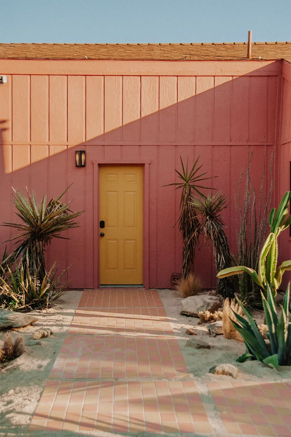 Desert home exterior painted pink with a yellow door.