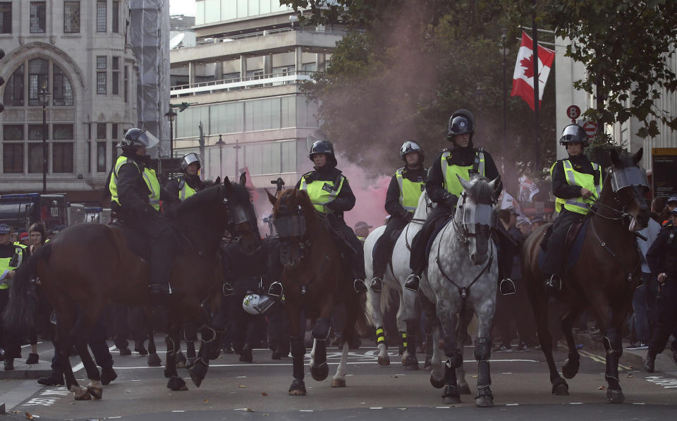 Mounted police horses react to a flare going off during an anti-fascist demonstration held in protest against a rival march by the Football Lads Alliance march, London, Saturday, Oct. 13, 2018. (AP Photo/Alastair Grant)