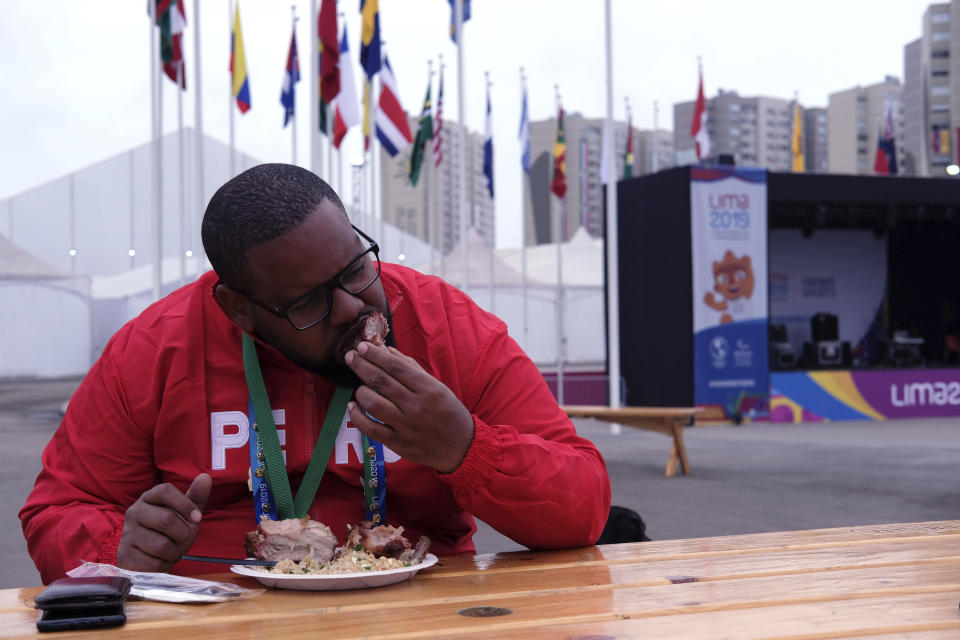 In this Aug. 8, 2019 photo, Rodrigo Rosa, a Brazilian who worked for the event organizing at the Pan American Games eats pork and chaufa fried rice at the international center outside the Pan American athletes' village in Lima, Peru. Peruvian food was the star at the recent Pan Am Games held in Latin America’s culinary capital. Athletes from countries across the Americas tasted the highly-regarded cuisine that blends indigenous traditions with European, African and Asian influences with an abundance of seafood from the Pacific Ocean’s cold Humboldt current. (AP Photo/Luis Andres Hena