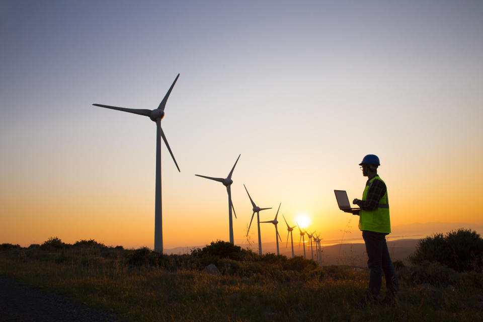 A person with a laptop inspecting wind turbines.