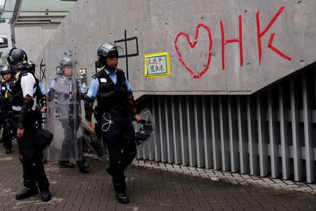 Riot police officers walk past a wall covered with messages following a day of violence over an extradition bill, in Hong Kong