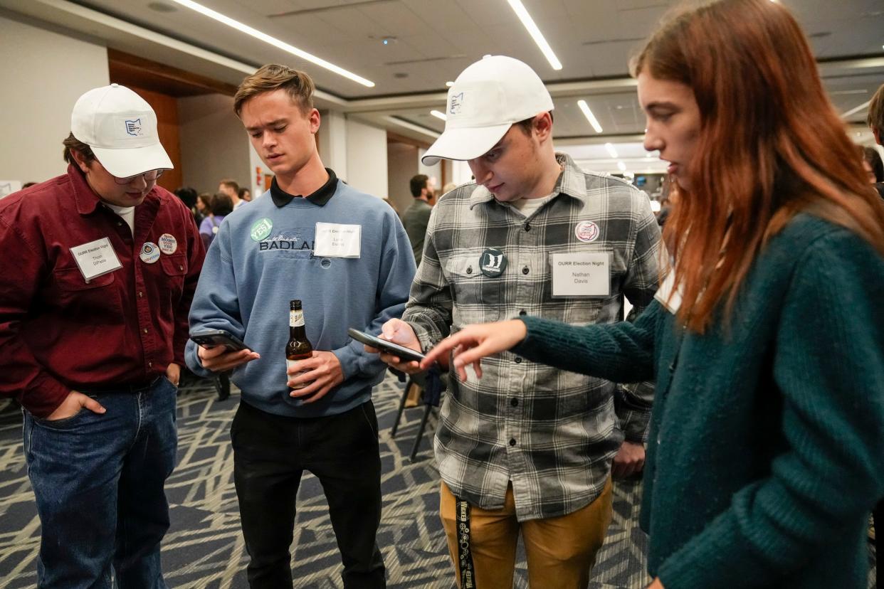 Ohio State University College Democrats, from left, Thom DiPaola, Luke Evans, Nathan Davis and Katie Seewer check election results on their phones during a gathering for supporters of Issue 1 at the Hyatt Regency Downtown in Columbus.