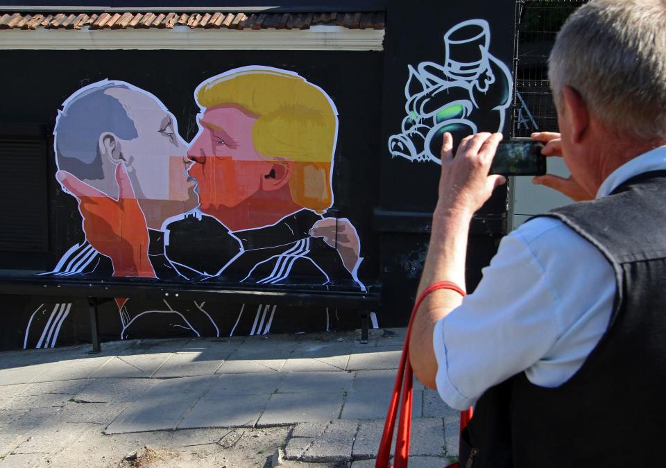 A man photographs a mural on a restaurant wall depicting US Presidential hopeful Donald Trump and Russian President Vladimir Putin greeting each other with a kiss in the Lithuanian capital Vilnius on May 13, 2016.&nbsp;