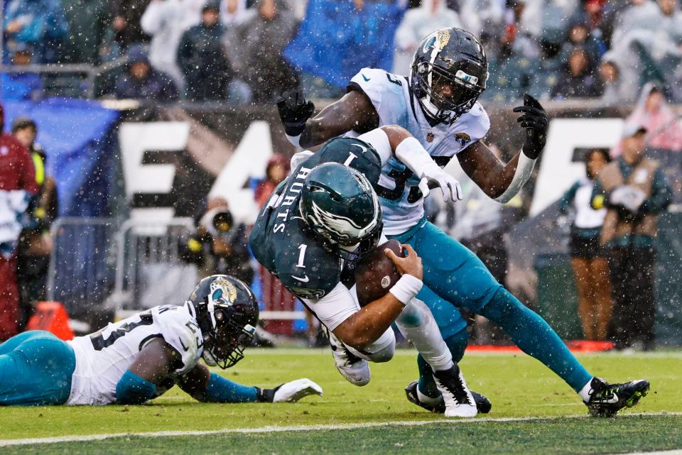 Philadelphia Eagles quarterback Jalen Hurts (1) scores a rushing touchdown past Jacksonville Jaguars cornerback Josh Thompson (23) and linebacker Devin Lloyd (33) during the first quarter of an NFL football game, Sunday, Oct. 2, 2022, in Philadelphia.