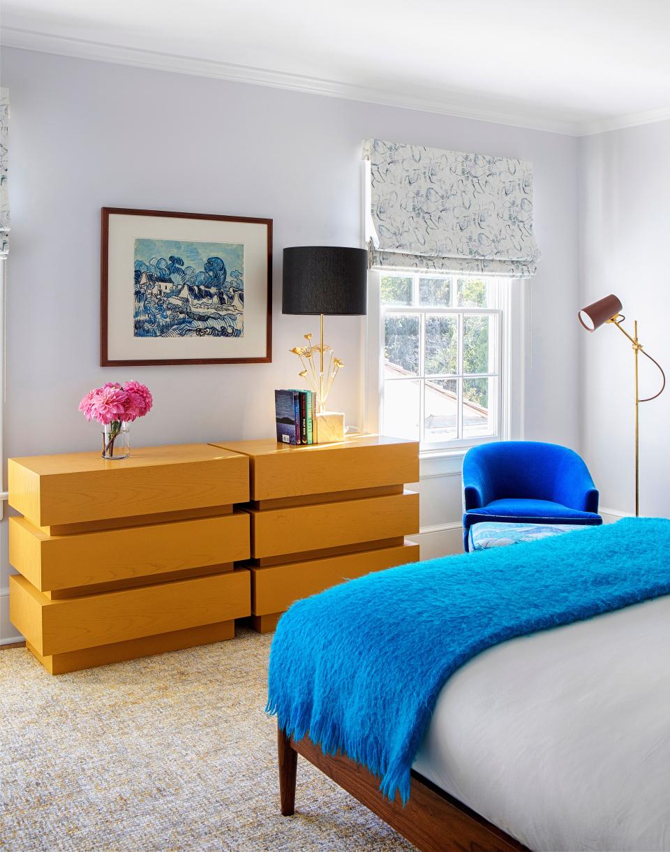 The second guest bedroom features a funky stacked-box chest dresser by Lawson Fenning. Above the dresser is an oil-on-paper painting, T-Shirts, by Alex Dodge, from the Klaus Von Nichtssagend Gallery. The vintage chair, from 1stDibs, was reupholstered with bright blue fabric, from Holland & Sherry. The bed is by West Elm, and the rug below it is from Stark Carpet. The floor lamp is from Circa Lighting.