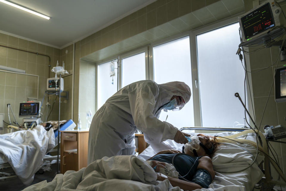 A nurse wearing a special suit to protect herself against coronavirus, treats a patient with COVID-19 in the ICU department of the emergency hospital in Lviv, Western Ukraine, Saturday, Jan. 9, 2021. Ukraine imposed a broad lockdown Friday, but many medical workers in the country fear that it came too late and the long holidays, during which Ukrainians frequented entertainment venues, attended festive parties and crowded church services, will trigger a surge in new coronavirus infections. (AP Photo/Evgeniy Maloletka)