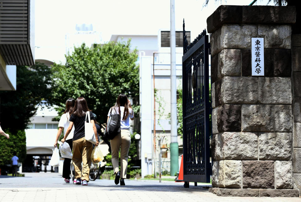FILE - In this Thursday, Aug. 2, 2018, file photo, people walk into Tokyo Medical University in Tokyo. The medical university confirmed Tuesday, Aug. 7, 2018, after an internal investigation that it systematically altered entrance exam scores for years to keep out female applicants and ensure more men became doctors. The manipulated all entrance tests results since 2000 or even earlier.T he Japanese plate at right reads: "Tokyo Medical University." (Ayaka Aizawa/Kyodo News via AP, File)