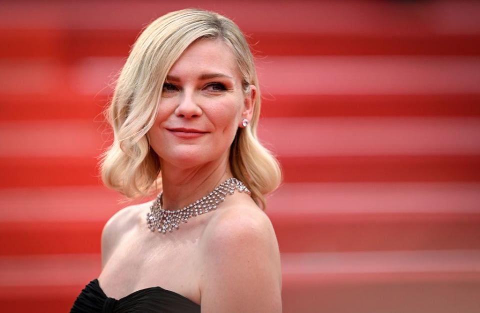kirsten dunst on a red carpet in a black strapless dress