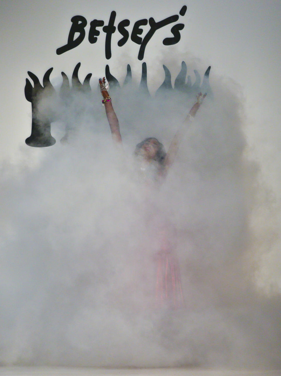 A model stands in a plume of smoke as fashion from the Betsey Johnson Fall 2014 collection is modeled during New York Fashion Week on Wednesday Feb. 12, 2014. (AP Photo/Bebeto Matthews)