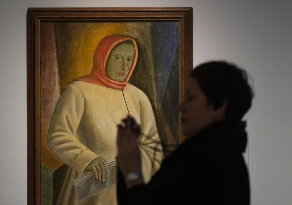 A woman takes photos next to the painting by Ukrainian artist Vasyl Sedliar called 'Portrait of Oksana Pavlenko' during the inauguration of the Ukraine art exposition at the Thyssen-Bornemisza museum in Madrid, Spain, Monday, Nov. 28, 2022. Against a backdrop of Russian attacks, border closures and a nail-biting journey across Europe, Madrid's Thyssen-Bornemisza National Museum has teamed up with Kyiv's National Art Museum of Ukraine to secretly bring dozens of Ukrainian 20th century avant garde artworks by road to the Spanish capital for a unique exhibition and statement of support for the war-torn country. (AP Photo/Paul White)