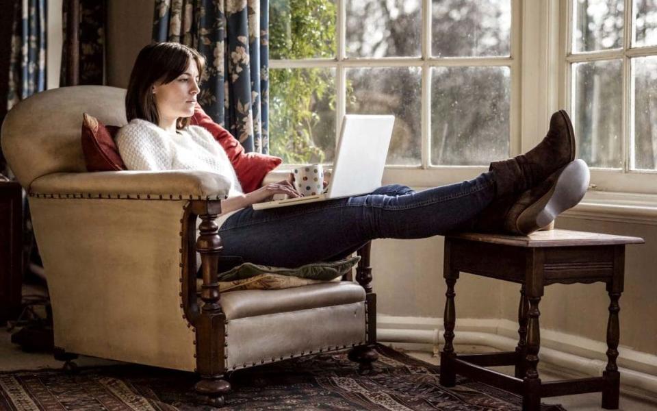 woman using laptop computer - with her feet up - Mint Images/Alamy