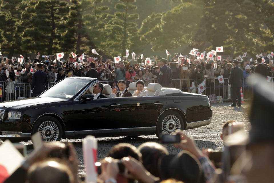 Japanese Emperor Naruhito and Empress Masako wave to spectators during the royal motorcade in Tokyo, Sunday, Nov. 10, 2019. (AP Photo/Jae C. Hong)